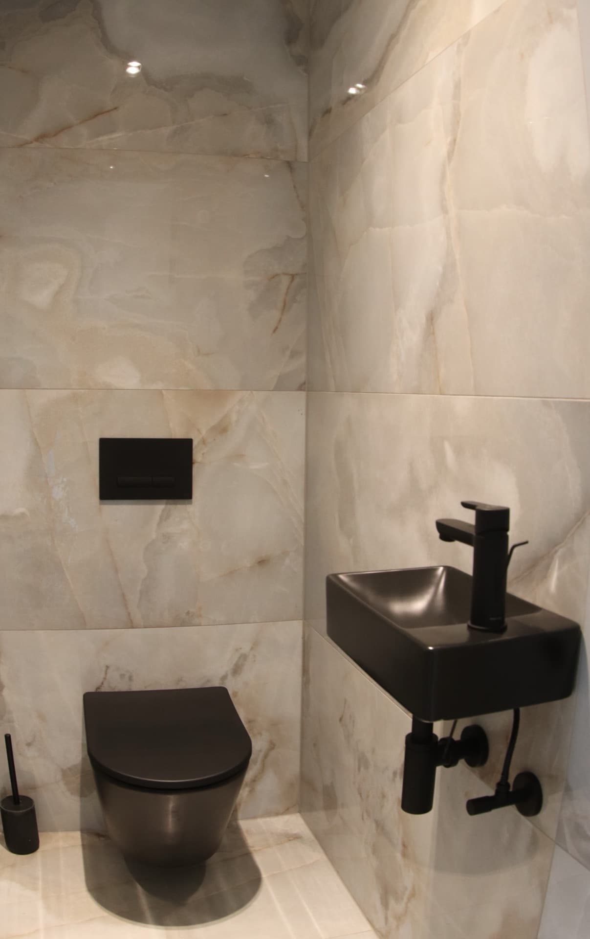 Guest WC clad in onyx marble with matte black fixtures